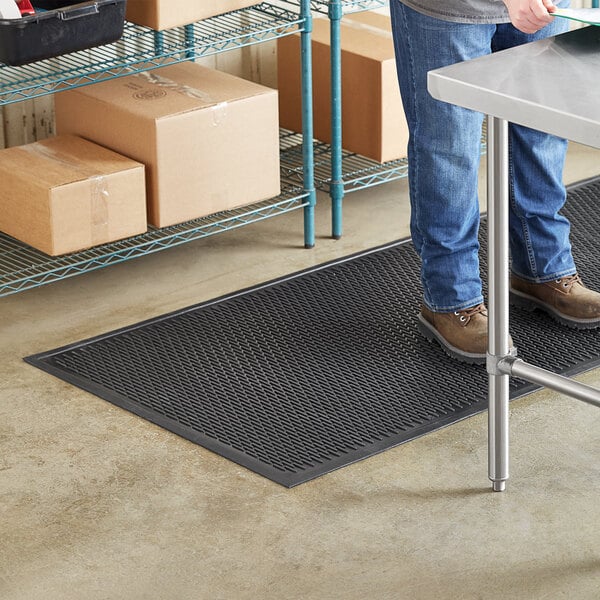 A person standing on a black Lavex heavy-duty rubber safety mat.