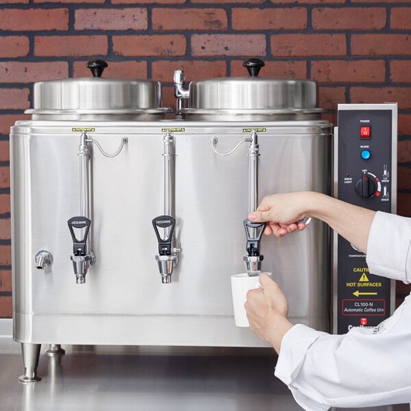 A person pouring coffee into a Cecilware automatic coffee urn.