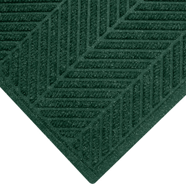 A close-up of a green M+A Matting WaterHog Southern Pine mat with a chevron pattern border.