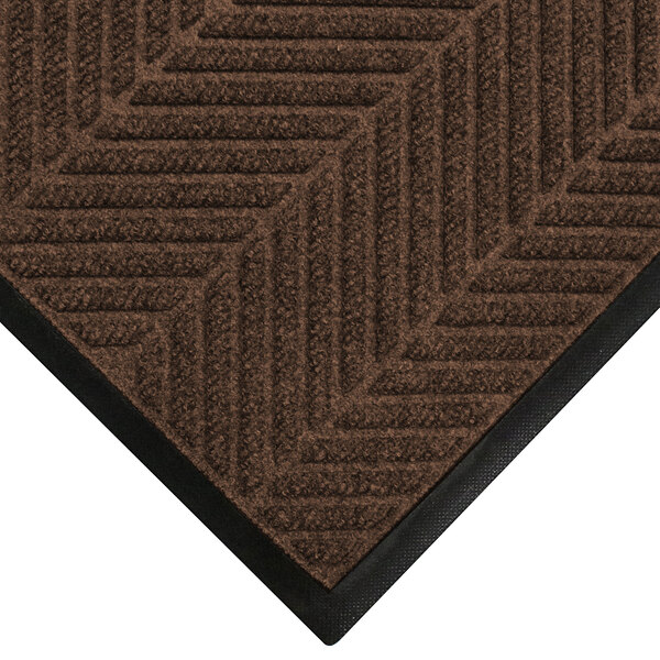 A brown WaterHog door mat with black trim on a carpet.