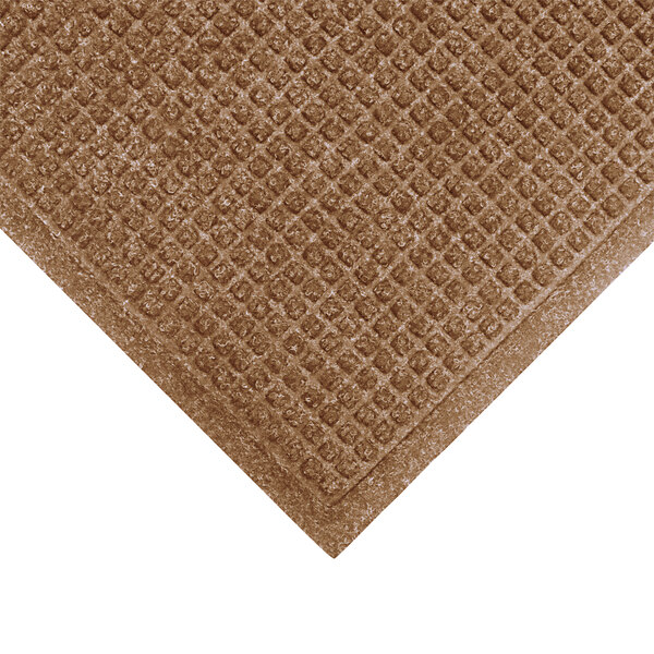 A close-up of a brown M+A Matting WaterHog mat with a square pattern.