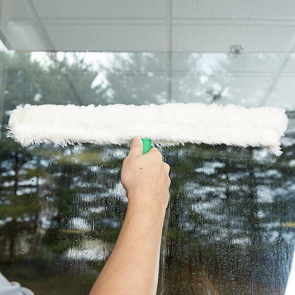 A person cleaning a window with a Unger white plastic T-bar.