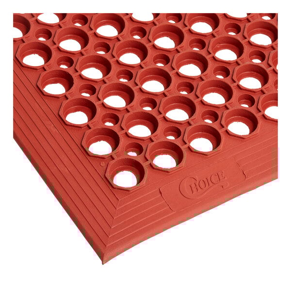 A red rubber Choice anti-fatigue floor mat with holes in the middle.