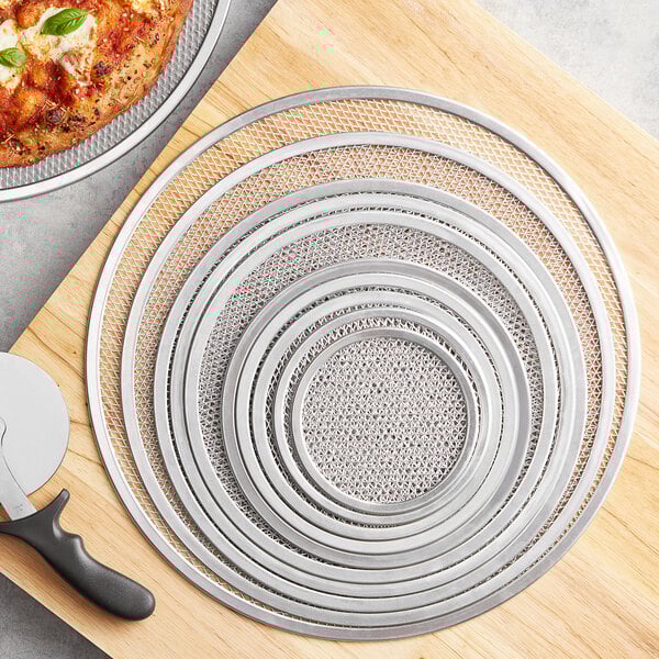 A pizza on a Choice aluminum pizza screen on a cutting board.