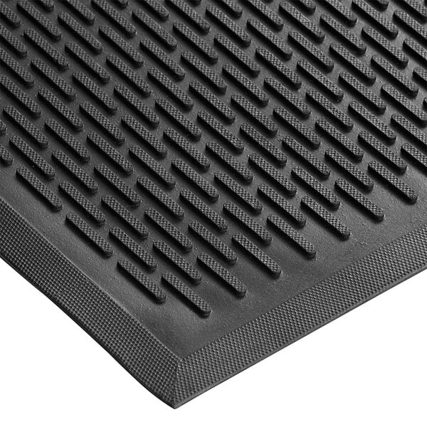 A close-up of a black rubber Choice Ridge-Scraper Top safety mat with a patterned design.