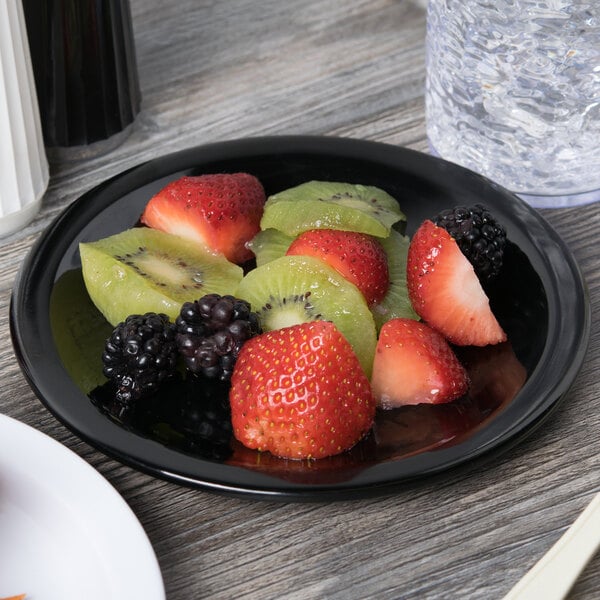 A Carlisle black melamine pie plate with fruit on a table.