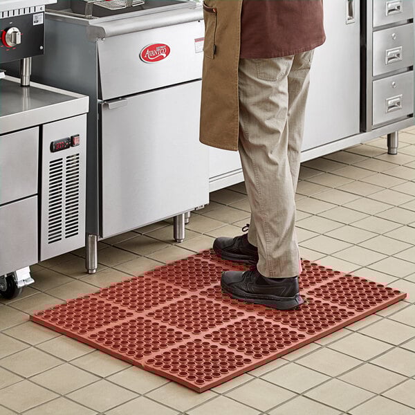A man standing on a red Choice anti-fatigue floor mat.