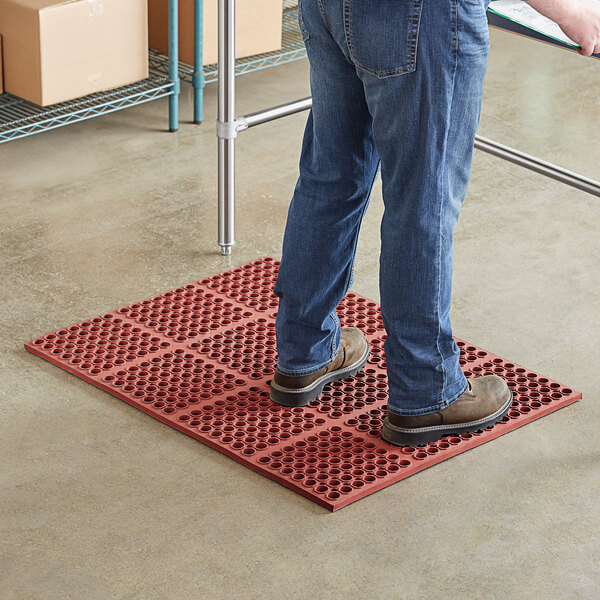 A man standing on a red Choice anti-fatigue floor mat.