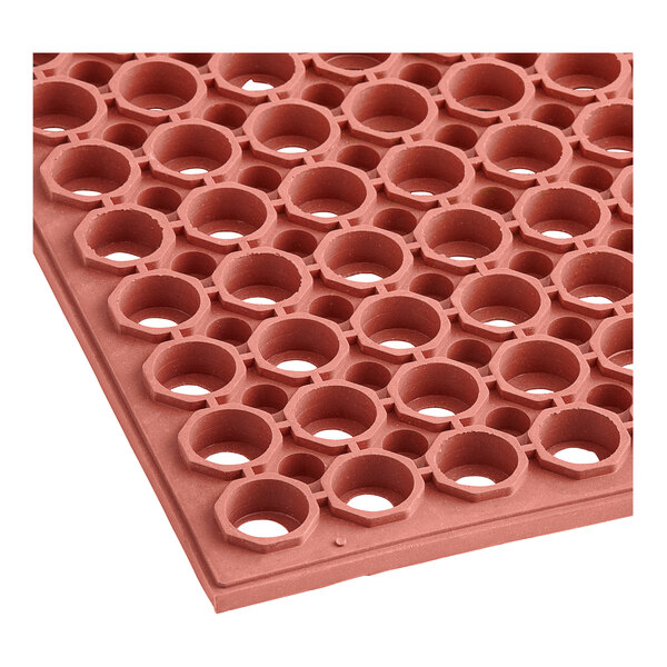 A close up of a red rubber Lavex floor mat with holes in it.