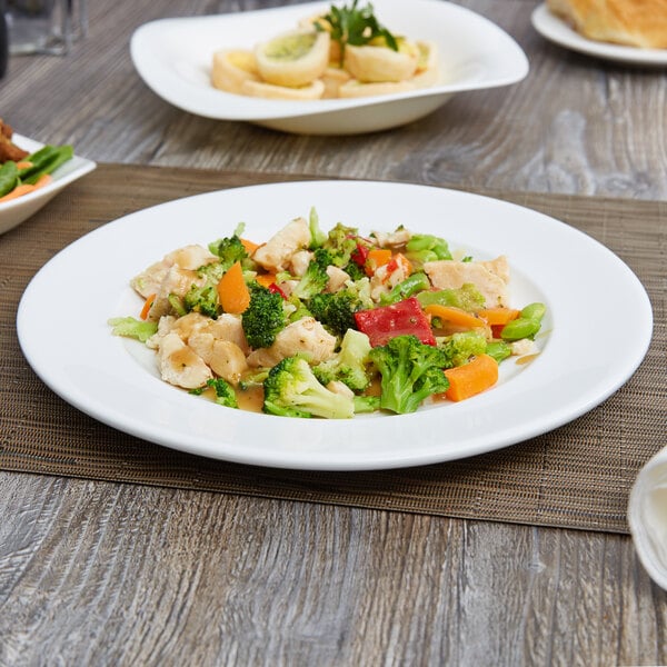 An Arcoroc white porcelain brunch plate with food, including rice and broccoli, on a table.