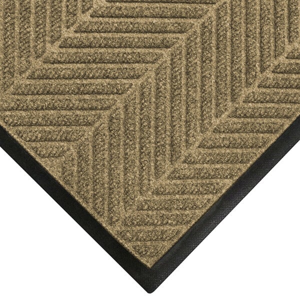 A khaki WaterHog mat with a black chevron border.