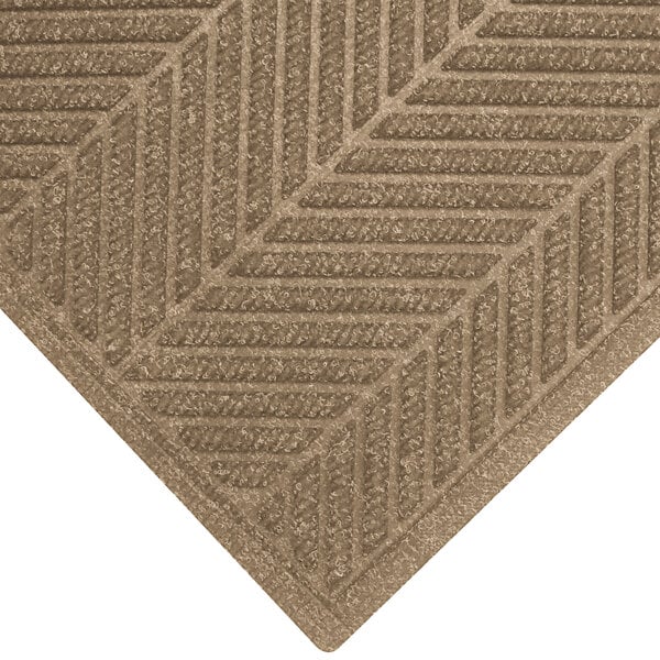 A close up of a khaki WaterHog mat with a chevron patterned border.