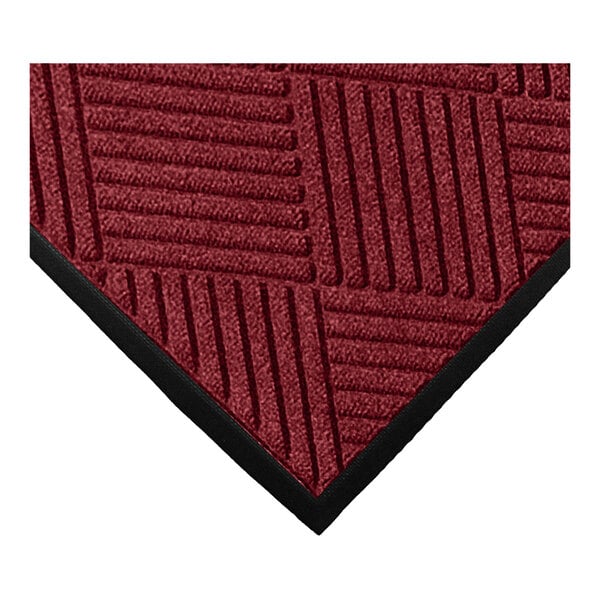 A close-up of a red textured mat with a geometric diamond pattern and a black rubber border.