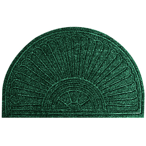 A green doormat with a fan shaped design on a surface.