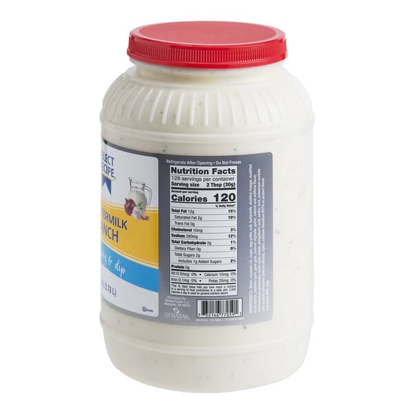 A large plastic jar with a red lid containing a creamy white dressing, featuring a nutrition facts label and partial product branding visible.