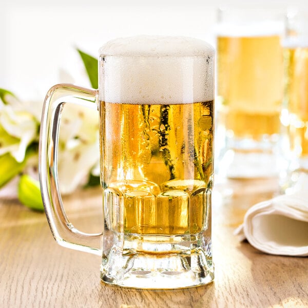 A Fortessa Basics Brew Pub beer mug filled with beer on a table with flowers.