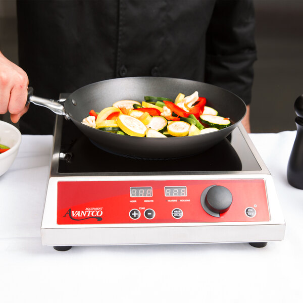 A person cooking vegetables in a Vollrath carbon steel non-stick fry pan on a stove.