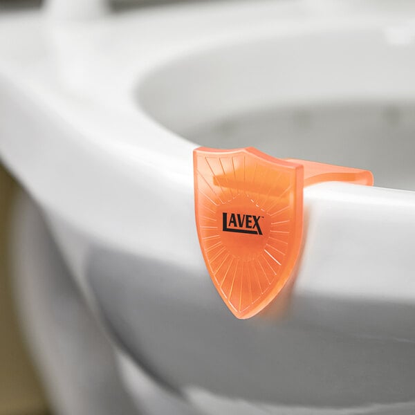 A white toilet with an orange Lavex Citrus Scent gel clip on the bowl.