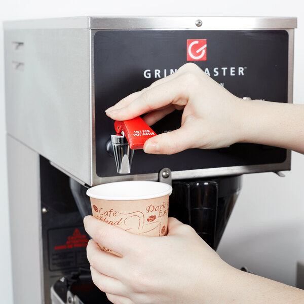 A Grindmaster coffee brewer on a counter in a corporate office cafeteria.