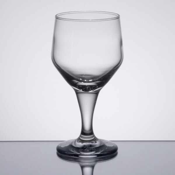 A close-up of a Libbey clear wine glass on a reflective surface.