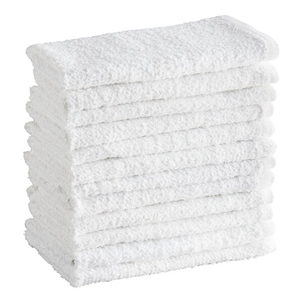A stack of twelve white textured terry towels neatly folded.
