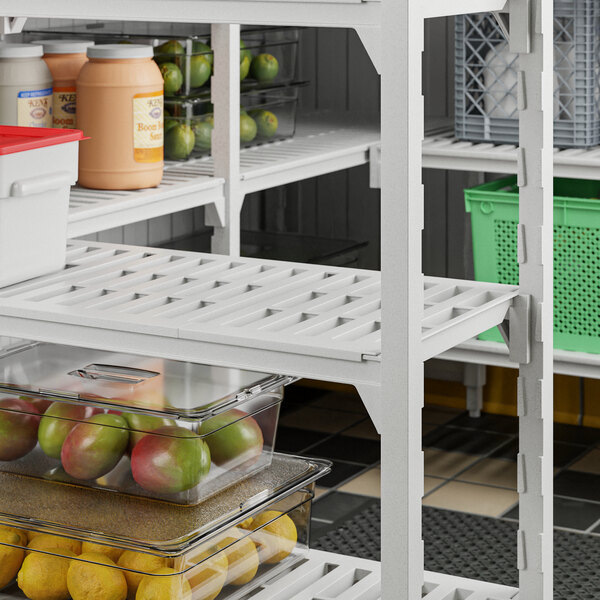 A white Cambro Camshelving Premium vented shelf with fruit in containers.