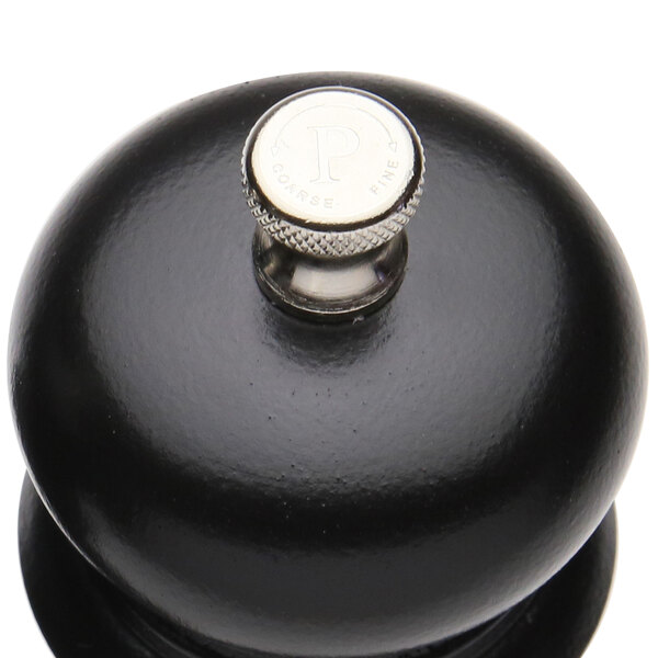 A black round pepper mill with a silver knob.