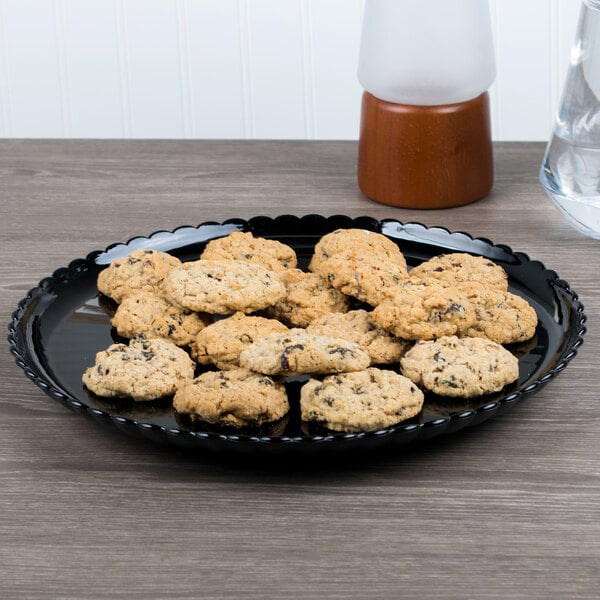 A black GET Mediterranean polycarbonate plate with cookies on a table.