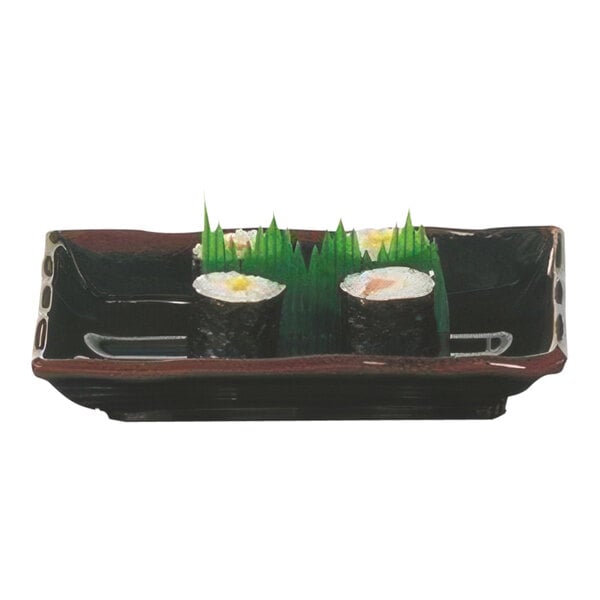 A rectangular black Thunder Group melamine plate with sushi rolls in it.