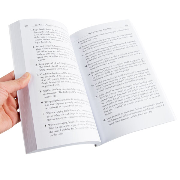 A hand holding open The Waiter, Waitress & Waitstaff Training Handbook