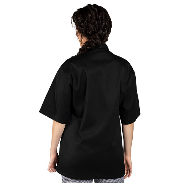 A woman wearing an Uncommon Chef black short sleeve chef coat.