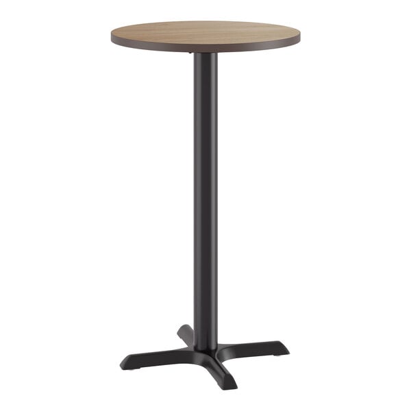 A round bar height table with a reversible birch and ash laminated top and a black cast iron base.