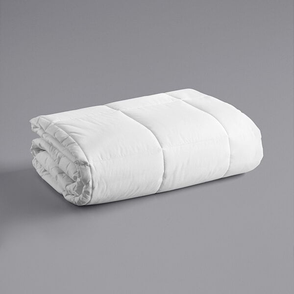 A white Oxford cotton and polyester hotel duvet insert folded up on a gray surface.