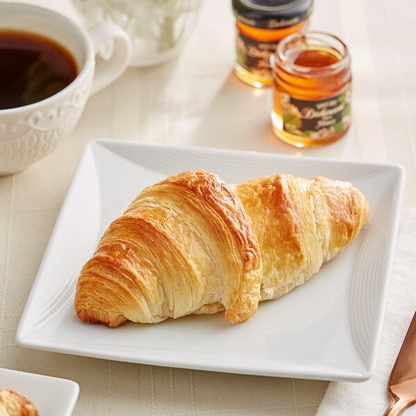 A white plate with a Bridor croissant on it and a cup of coffee.