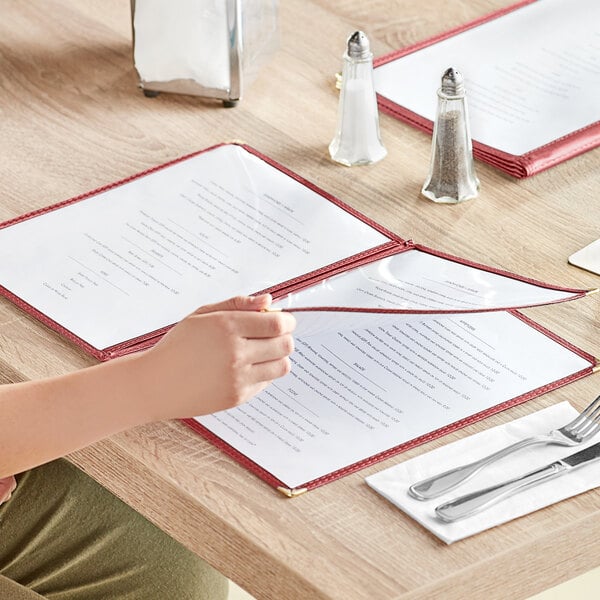A woman sitting at a table with a burgundy Choice menu cover on it.