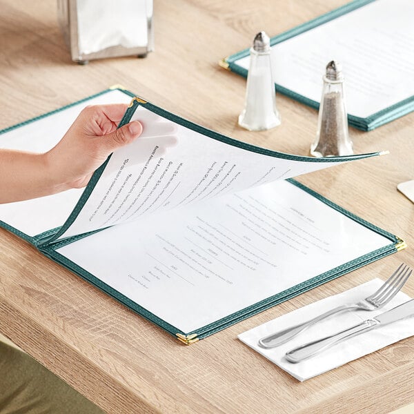 A person holding a green 8 1/2" x 11" menu cover with four pockets.