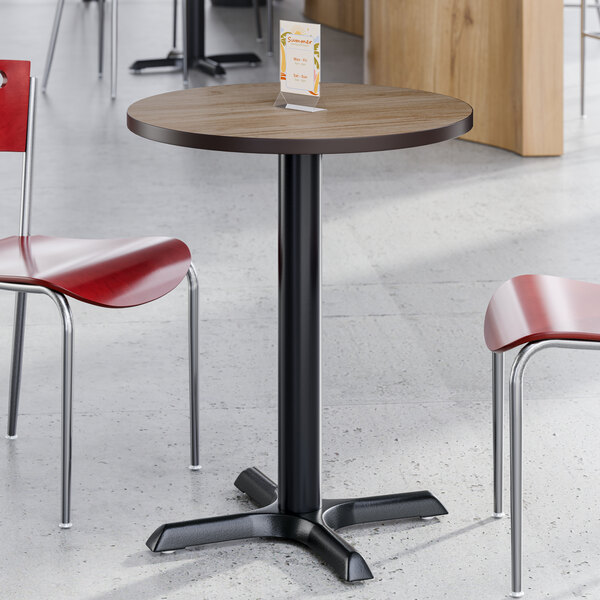 A round, standard height table with a reversible birch and ash laminated top and a black cast iron base.