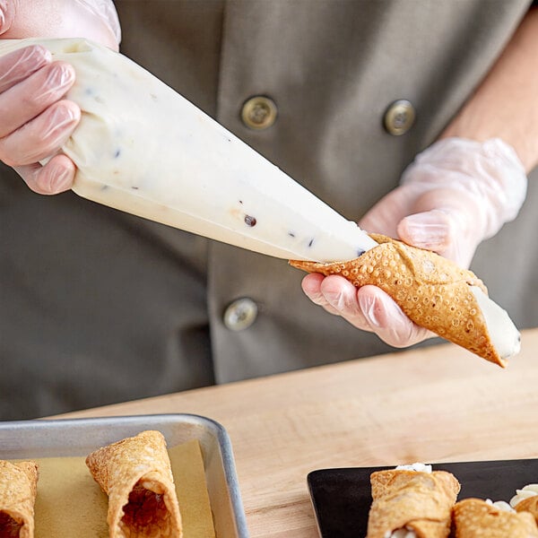 A person using a pastry bag to fill a cannoli with Brooklyn Cannoli Cream.