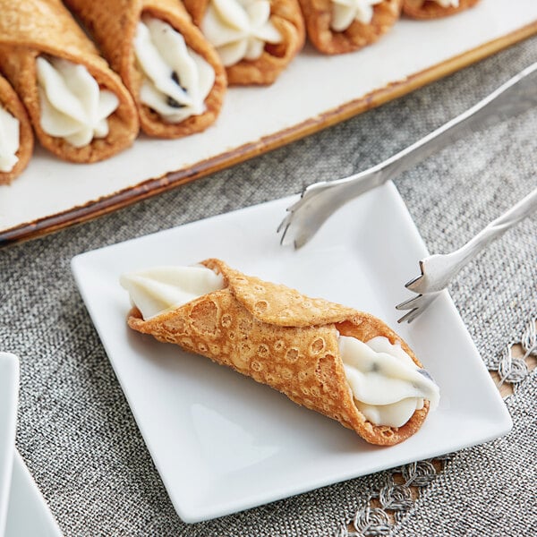 A plate of Brooklyn Cannoli mini cannoli shells filled with cream on a white surface.