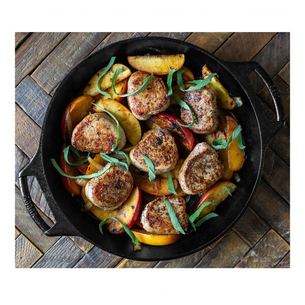 A Lodge cast iron baking skillet filled with meat and vegetables on a table.