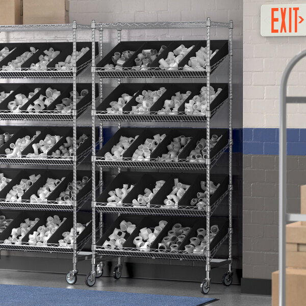 A Regency chrome metal shelving unit with slanted shelves holding black bins.
