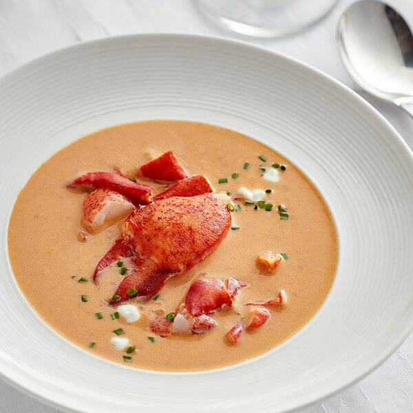 A bowl of lobster soup with a spoon on the side.