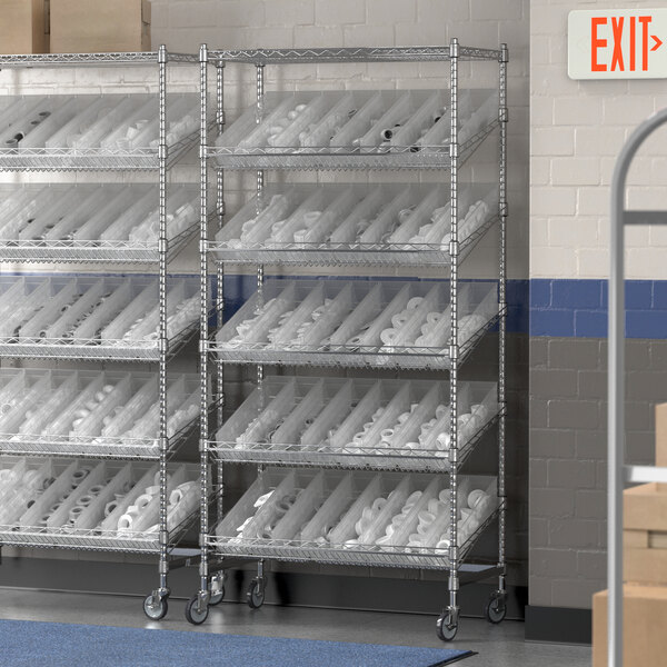 A Regency metal shelving unit with slanted shelves and clear plastic bins on it.