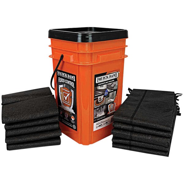 A large orange bucket with black bags of Quick Dam flood barriers next to it.