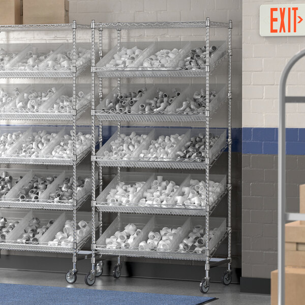 A Regency mobile metal shelving unit with clear plastic bins on slanted shelves.