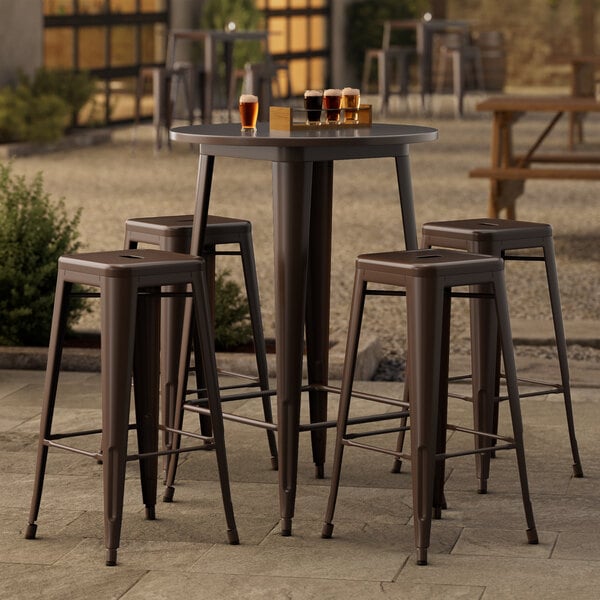 A Lancaster Table & Seating Alloy Series round copper bar height table with four backless barstools on a patio.