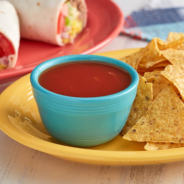 A plate of tortilla chips with red Pace Picante sauce on a table in a Mexican restaurant.