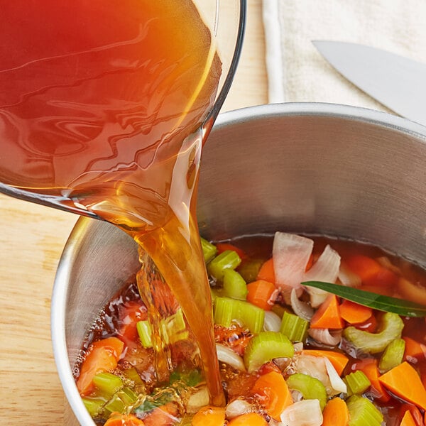 A can of Swanson Beef Broth being poured into a bowl of soup.