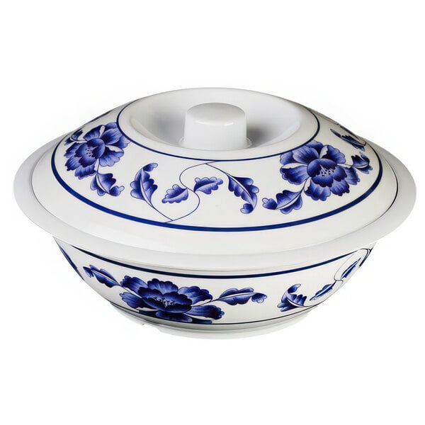 A white bowl with blue flowers on it and a lid with blue and white flowers.