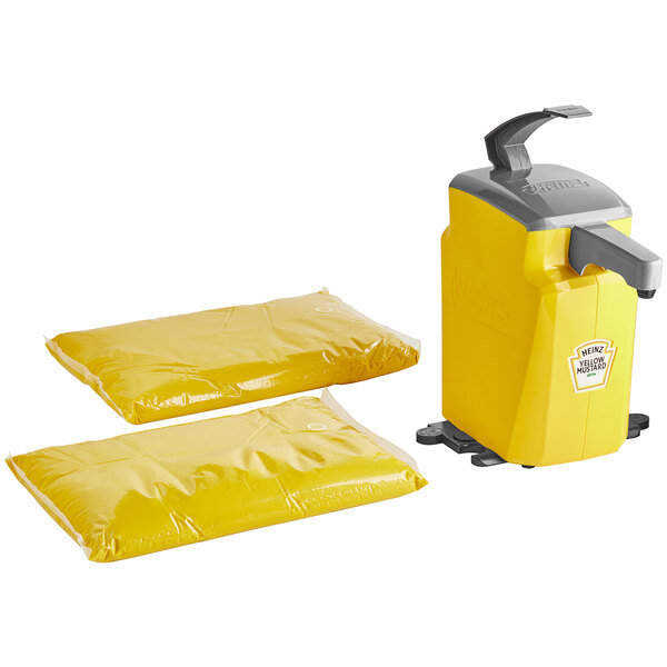 A yellow Heinz plastic countertop pump dispenser with two yellow Heinz mustard pouches.